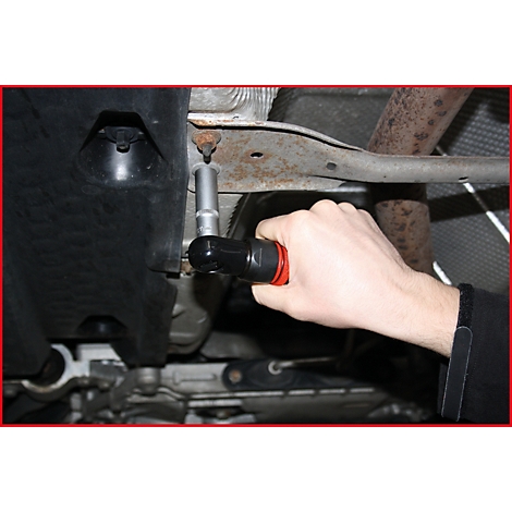 Hand mit Schraubenschlüssel an einem Fahrzeugteil. 